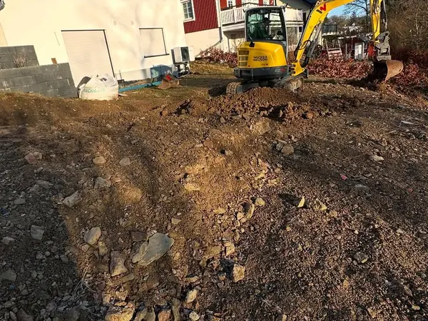 Bagger beim Ausheben des Erdreichs neben dem Haus