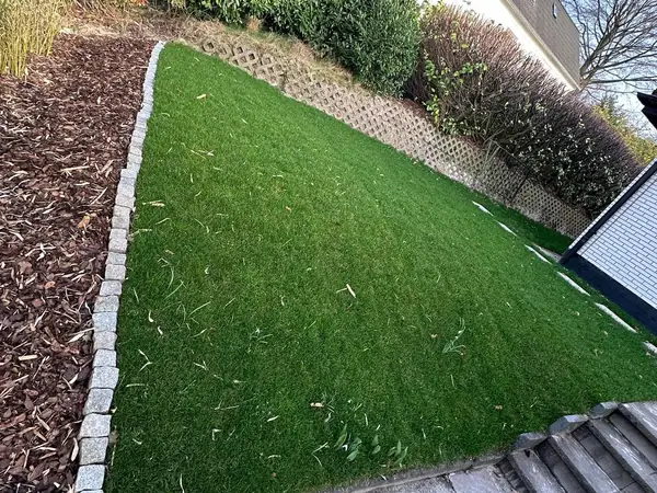 Rasenfläche mit eingefasstem Beet und Treppenabgang