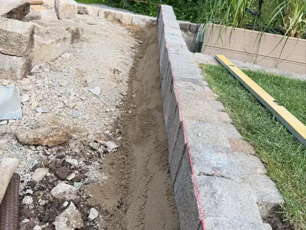 Neu gesetzte Natursteinmauer als Terrassenabschluss
